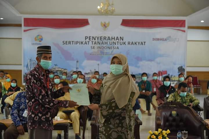 Bupati Masnah menyerahkan sertifikat tanah kepada rakyat secara simbolis.