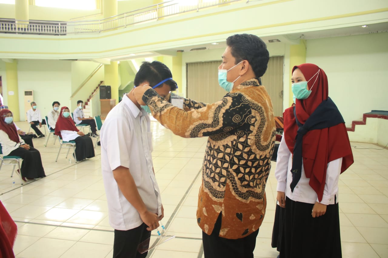 Wakil Rektor III Bidang Kemahasiswaan dan Kerja Sama, Dr. Bahrul Ulum, MAK memasangkan masker kepada peserta.(Foto:Bujangdek)