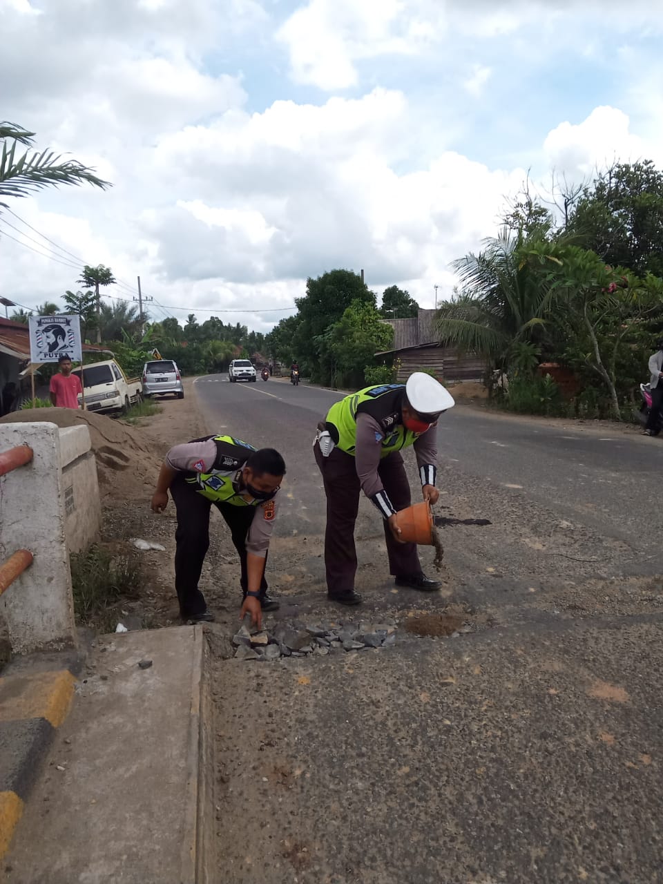 Aksi Bripka Doni dan Bripka Suhendri saat memperbaiki jalan yang berlubang di atas jembatan Desa Berembang.