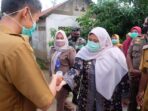 Bupati Masnah menjalani tes suhu badan sebelum menyalurkan bantuan kepada warga.