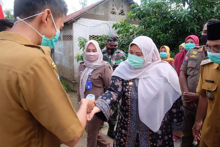Bupati Masnah menjalani tes suhu badan sebelum menyalurkan bantuan kepada warga.