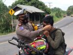 Kasat Lantas Polres Muaro Jambi, Iptu Firdaus memasangkan masker ke pengendara roda dua.