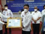 Pj. Sekda Alpian, S.E., MM saat menerima penghargaan peringkat 1 kepatuhan pelayanan publik.
